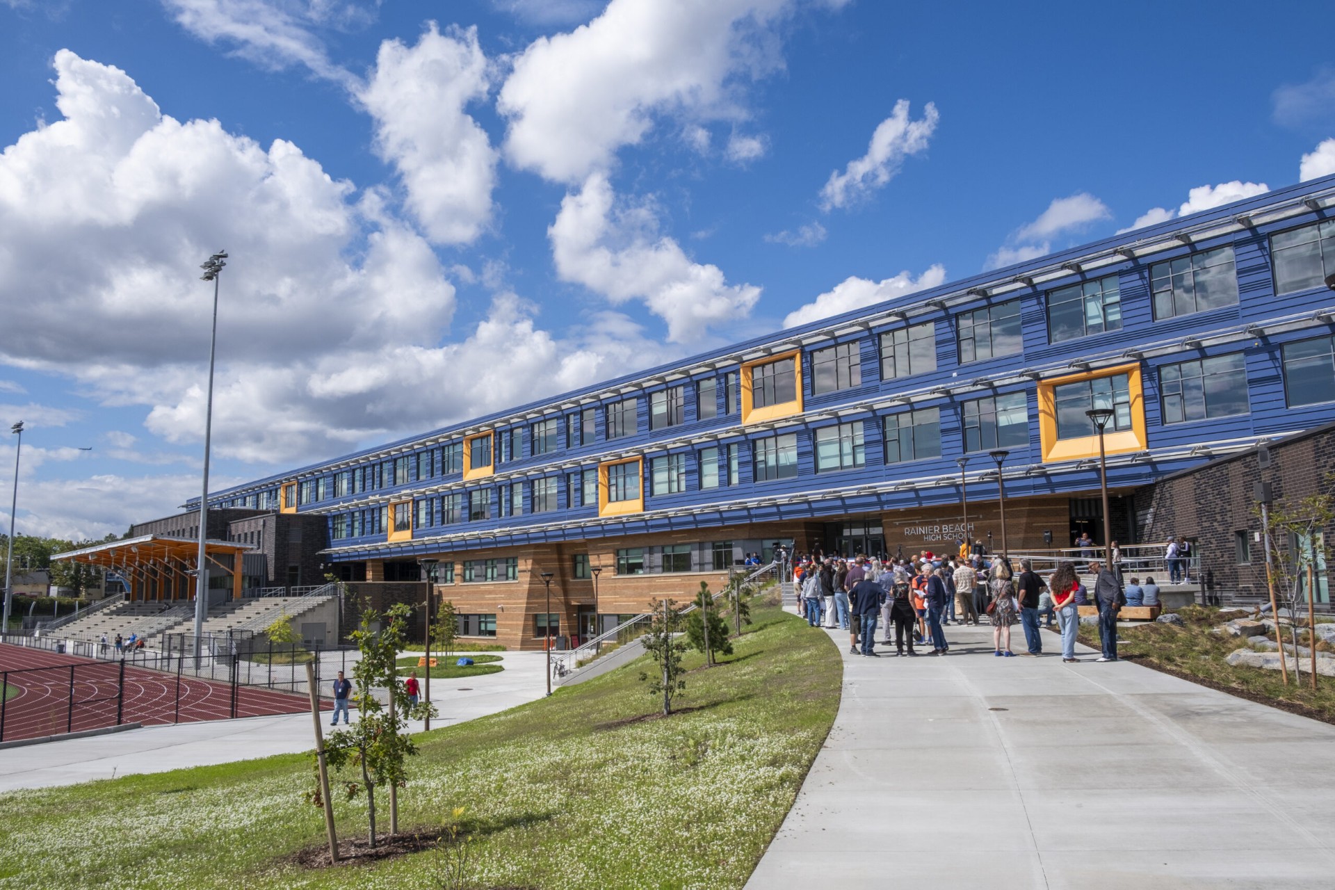 The new Rainier Beach High School building with its blue and orange facade, bleachers, and the track out front
